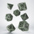 Photo of 7 polyhedral dice in gray with black numbers and fantasy design embellishments.