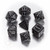 Photo of 7 polyhedral dice in black with silver numbers and design embellishments. Very gothy.