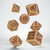 Photo of 7 polyhedral dice in beige with maroon numbers and fantasy embellishments.