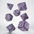 Photo of 7 polyhedral dice in purple with numbers and sci-fi design embellishments in white ink.