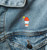 Close-up of a denim jacket showing the small, colorful embroidered shaved ice cup icon on the chest.
