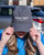 Woman modeling the gray baseball cap, pulling the brim down slightly over her eyes.