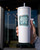 Hand holding the white tumbler with straw outside a store, showing the 'FLAVOR YOUR LIFE' logo.