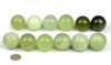 Set of 12 green serpentine jade spheres, arranged by tone, with coin for scale (white background)