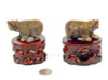 Pair of natural brown nephrite jade bear carvings on wooden stands, angled view under studio lighting