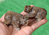 Pair of hand-carved brown nephrite jade bear figurines shown in hand under natural light