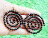 Koru-inspired spiral earrings made of black agate beads under natural light