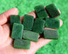 G026541A Multiple Variant A uncarved Canadian jade plaques with visible mineral inclusions held outdoors.