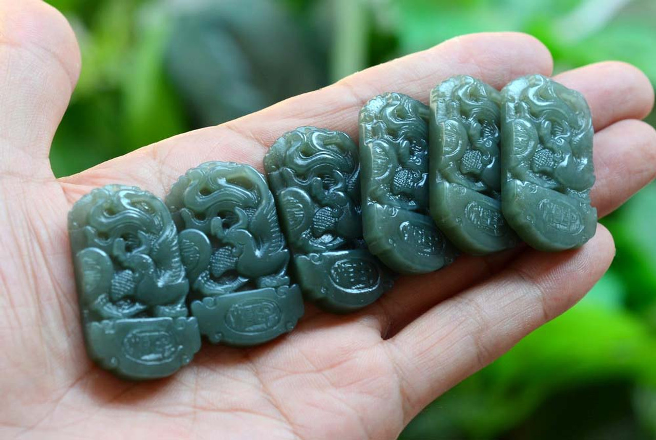 Item 4 - Group of darker-tone phoenix pendants in hand under natural light