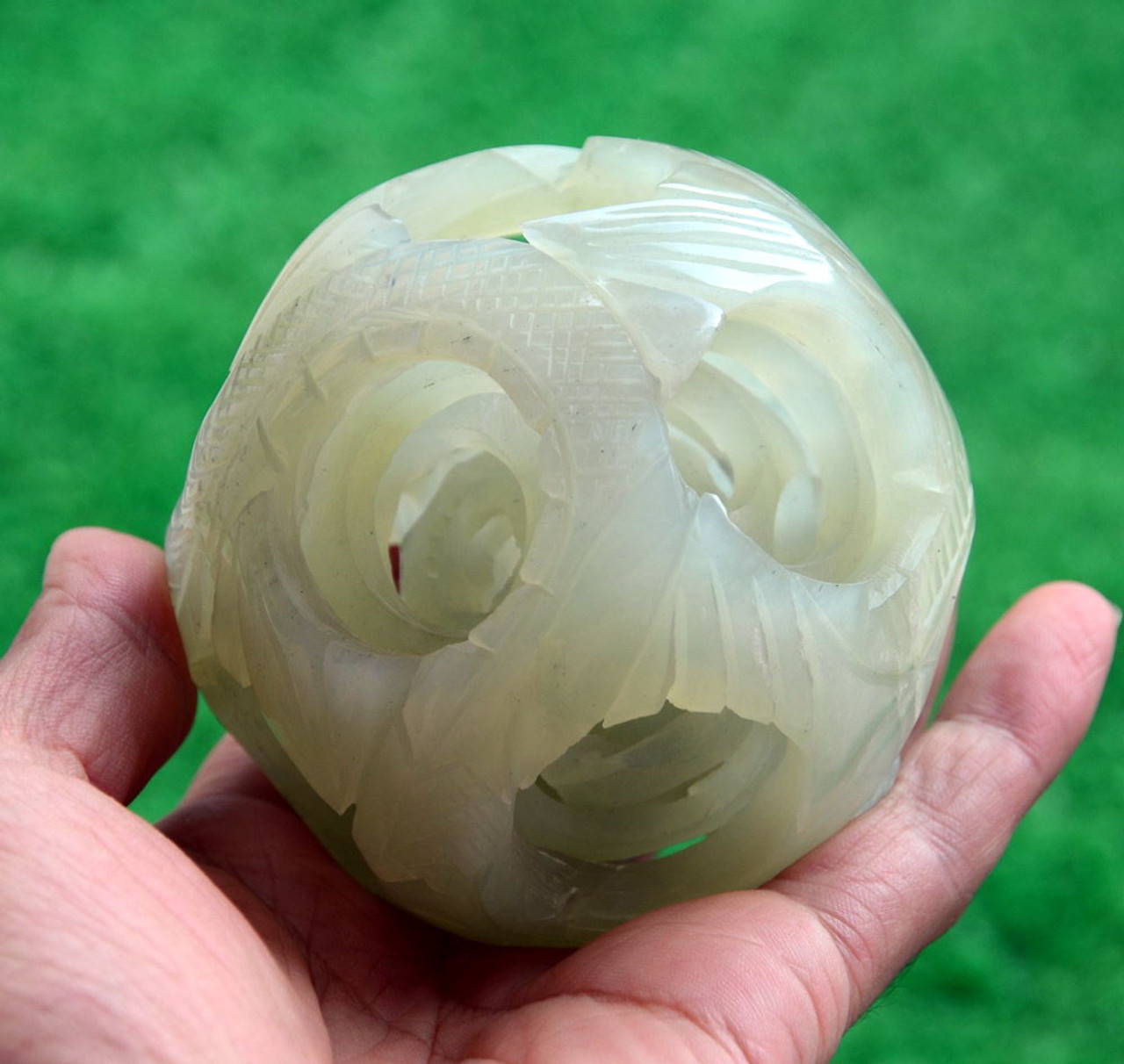 Close-up of jade puzzle ball showing abstract dragon and phoenix pattern