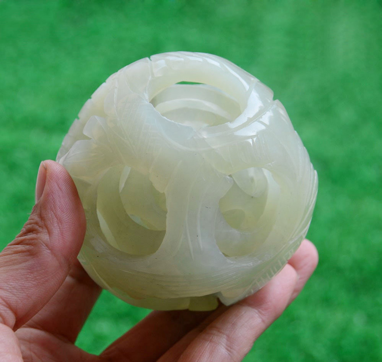 Hand holding jade puzzle ball to showcase size and intricate details