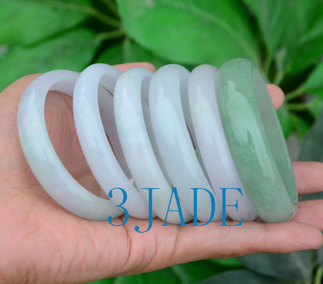 Set of jadeite bangles in hand under natural light.