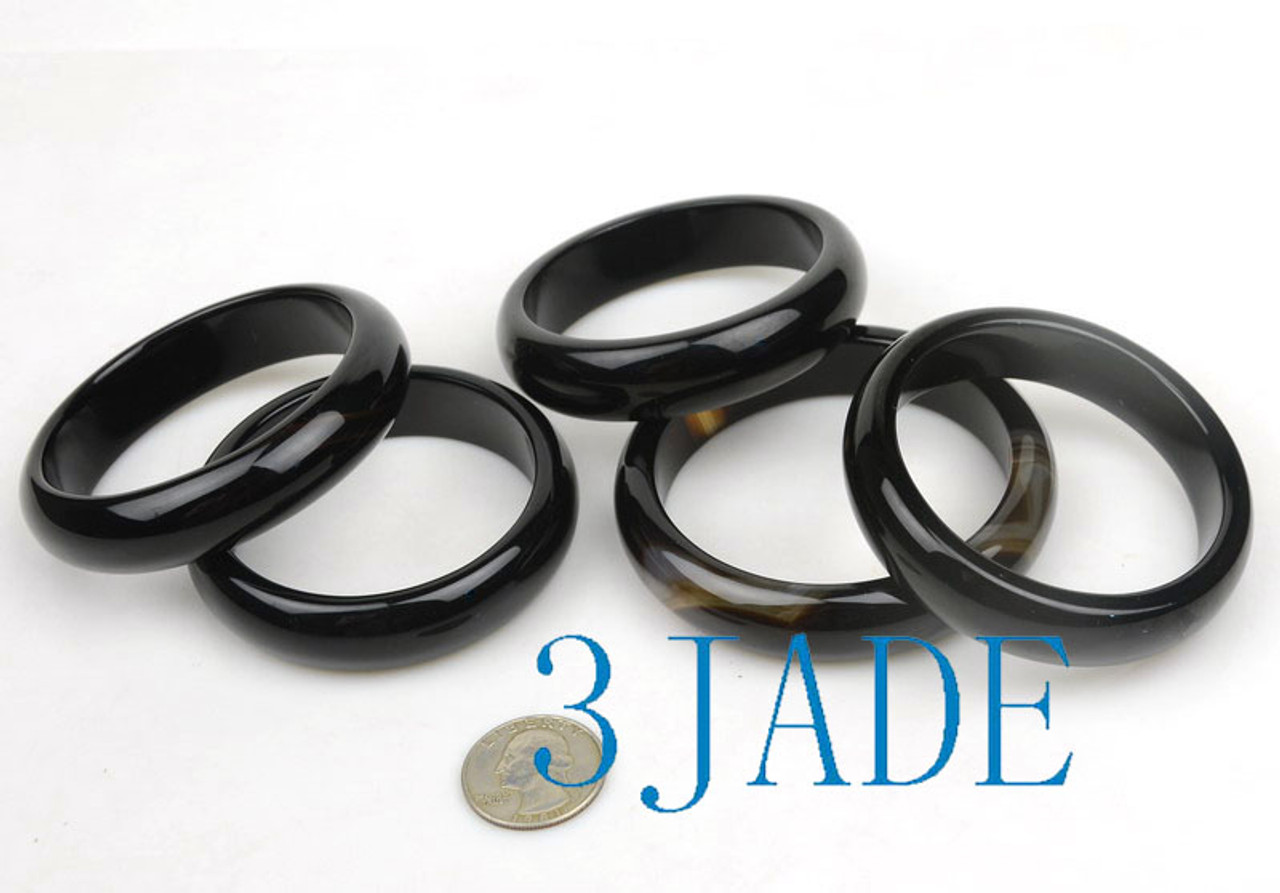 Group of glossy black agate bangles under studio lighting.