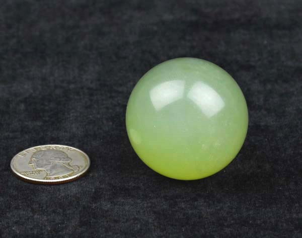 Close-up of one pale green jade ball with coin (black background)