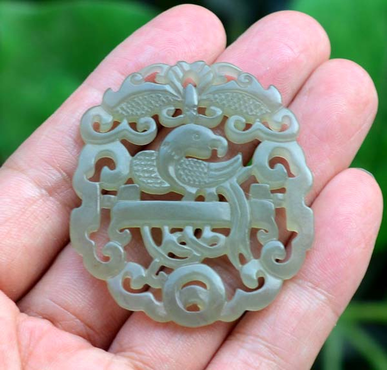 Natural light photo of a single nephrite jade parrot pendant with intricate carving