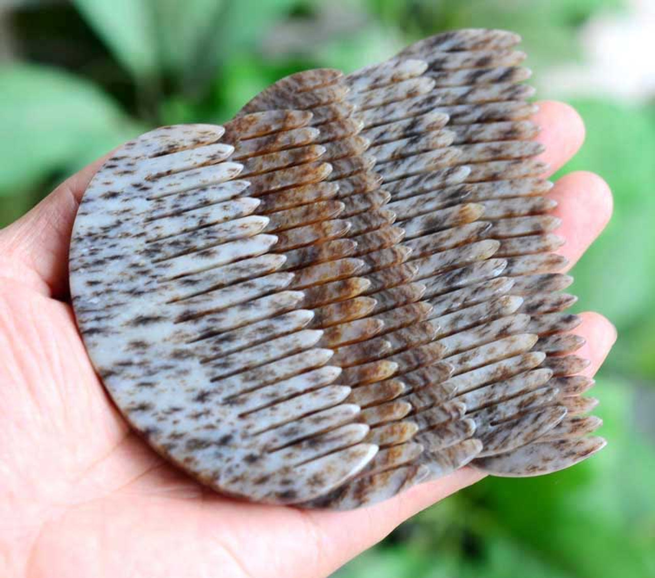 Hand holding the nephrite jade combs under natural light, showing the true color of jade