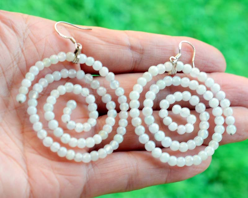 Koru-inspired spiral earrings made of jadeite beads under natural light