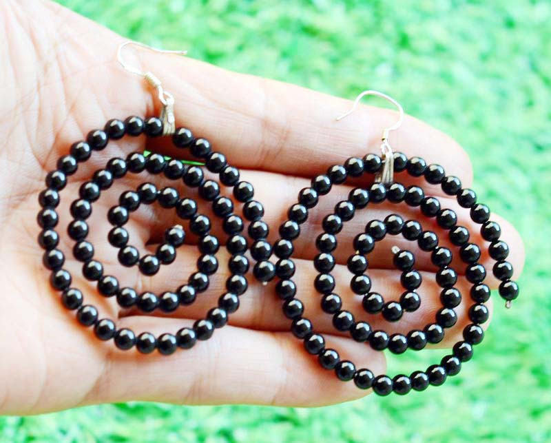 Koru-inspired spiral earrings made of black agate beads under natural light