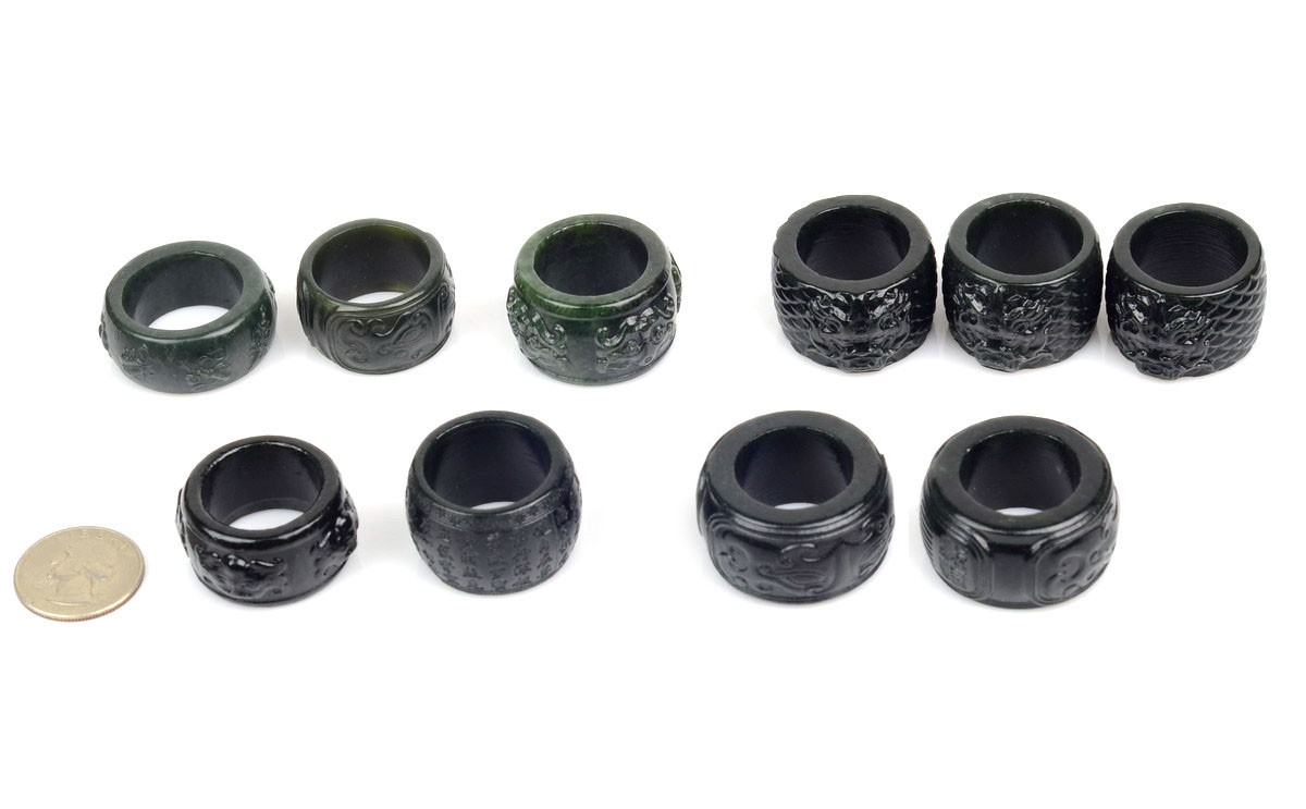 Assorted carved nephrite jade thumb rings under studio lighting