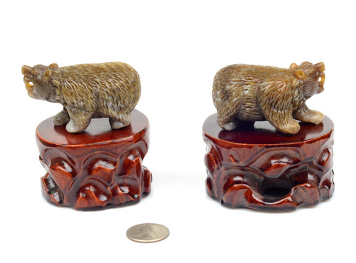Pair of natural brown nephrite jade bear carvings on wooden stands, angled view under studio lighting