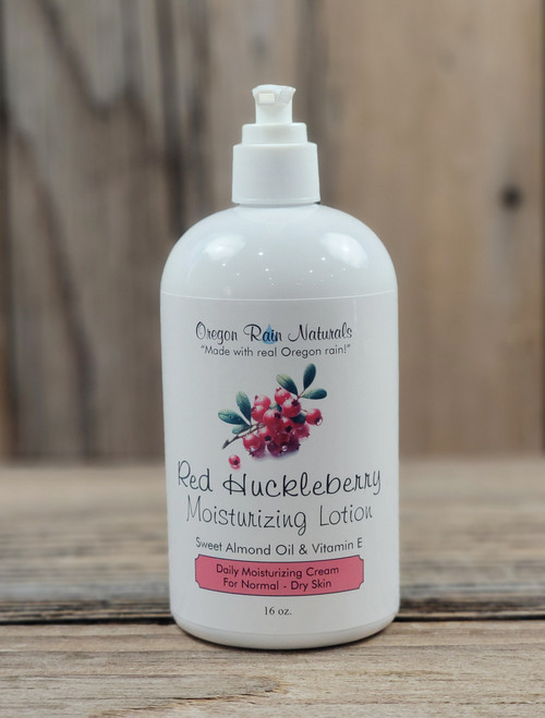 16 oz bottle of Red Huckleberry Moisturizing Lotion with berry graphics on the label, shown on a wooden background.
