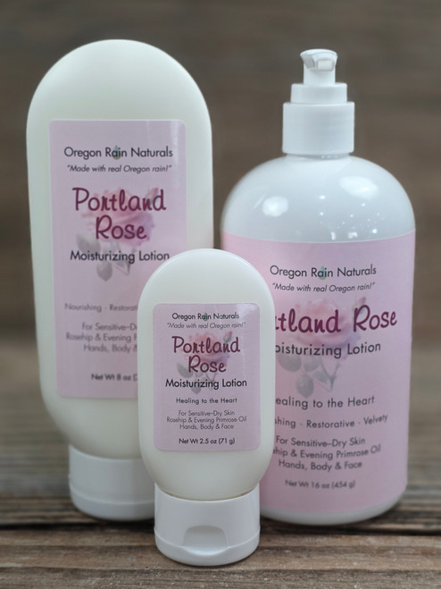 Portland Rose Moisturizing Lotion in three sizes—2.5 oz, 8 oz, and 16 oz bottles displayed on a wooden background.