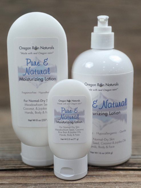 Pure & Natural Unscented Moisturizing Lotion in three sizes—2.5 oz, 8 oz, and 16 oz bottles displayed on a wooden background.