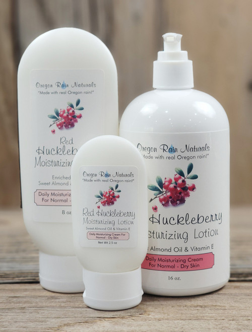 Red Huckleberry Moisturizing Lotion in three sizes—2.5 oz, 8 oz, and 16 oz bottles displayed on a wooden background.