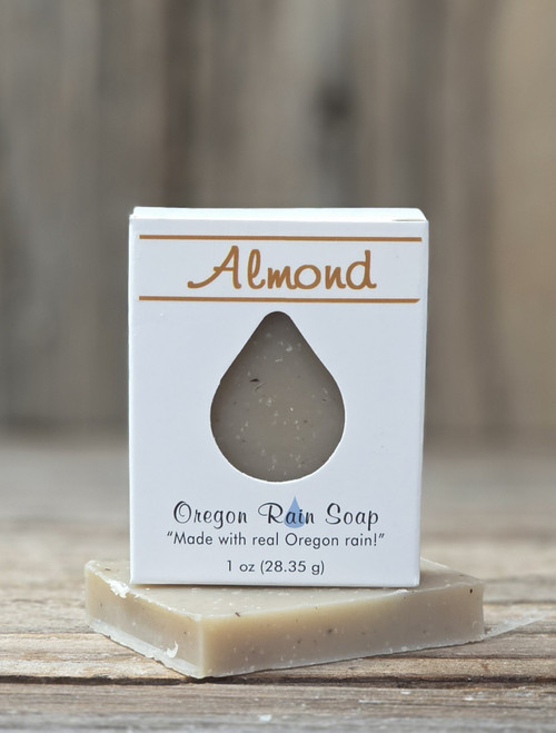 1 oz Almond Handmade Soap in a white box with a raindrop cutout showing the speckled almond bar, displayed on a wooden surface.