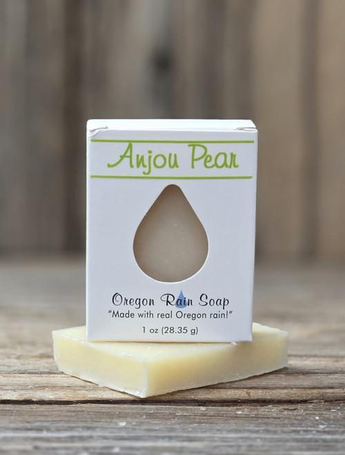 1 oz Anjou Pear Handmade Soap in a white box with a raindrop cutout showing the light pear‑colored bar, displayed on a wooden surface.