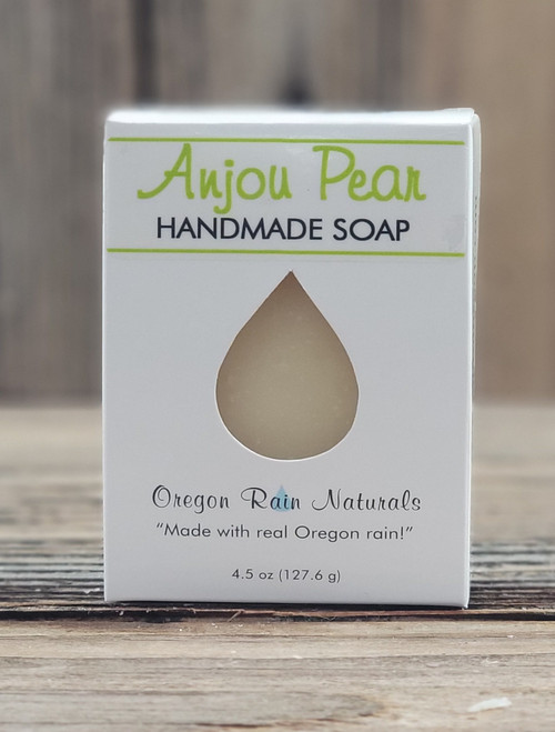 4.5 oz Anjou Pear Handmade Soap in a white box with a raindrop cutout showing the light pear‑colored bar, displayed on a wooden surface.