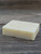 Unboxed Tea Tree + Oatmeal Pure Essence Handmade bar Soap sitting on a wooden platform.