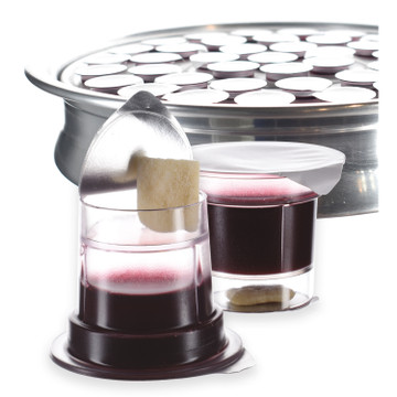 Simply Communion prefilled communion cup with Concord grape juice and bread, shown with lid partially peeled and tray of sealed cups behind