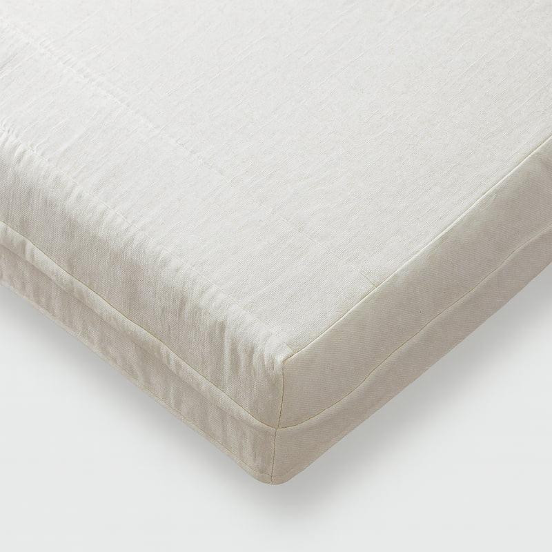 FoamOrder Certified Organic Cotton Muslin, close-up view of the edge of a soft, natural-colored organic cotton muslin mattress protector with a smooth texture and neat stitching.