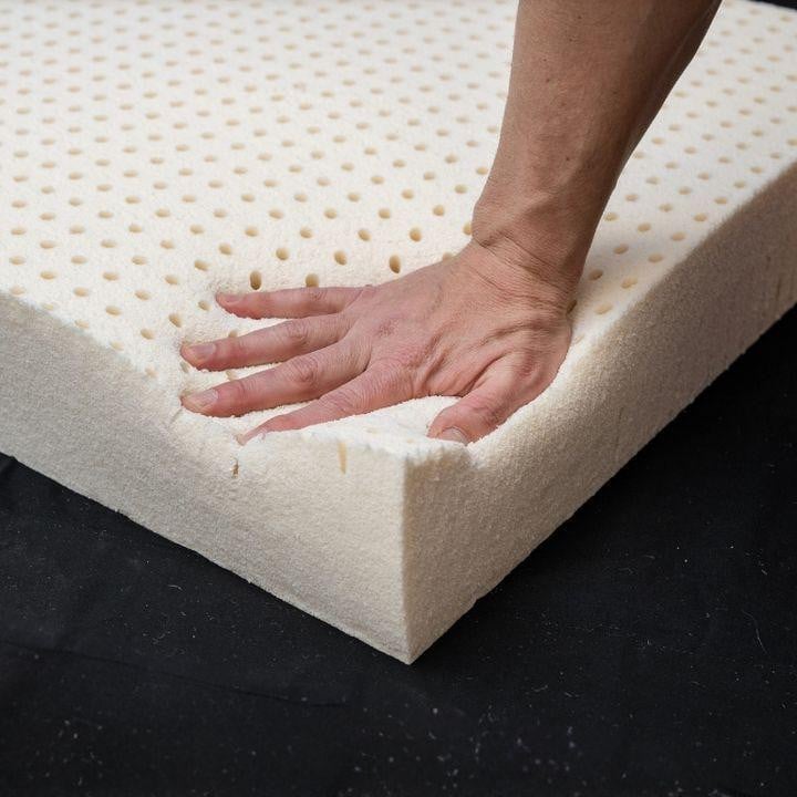 Latex Mattress Topper, person pressing down on soft, cushioned latex mattress topper with perforations for comfort and breathability.