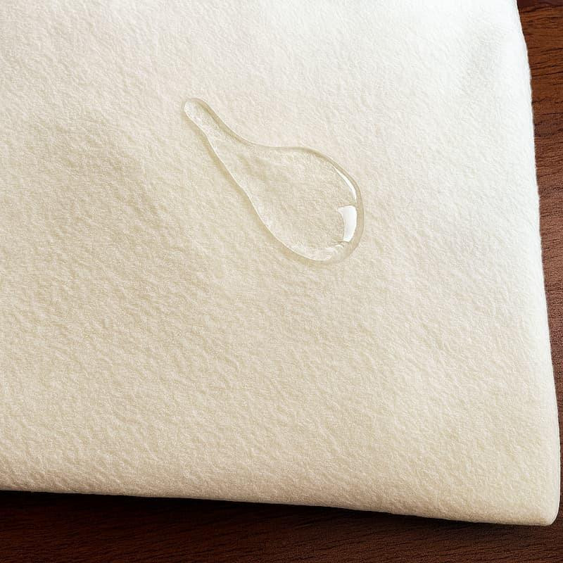 Organic Wool Mattress Protector, close-up of a soft, cream-colored fabric with a water droplet absorption feature.