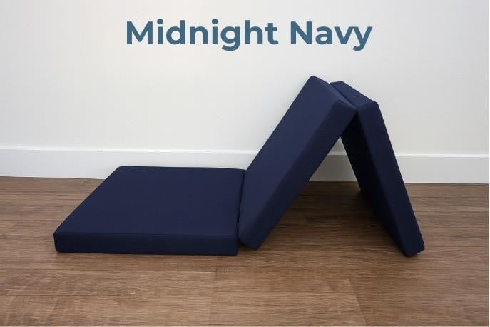 Tri-Fold Foam Mattress, navy blue foldable foam mattress in a partially folded position on wooden floor with white wall background.