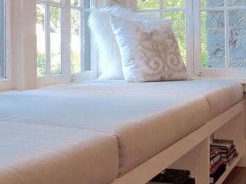 Custom Cushion, cozy white cushion with decorative patterns placed on a window seat in a bright room.