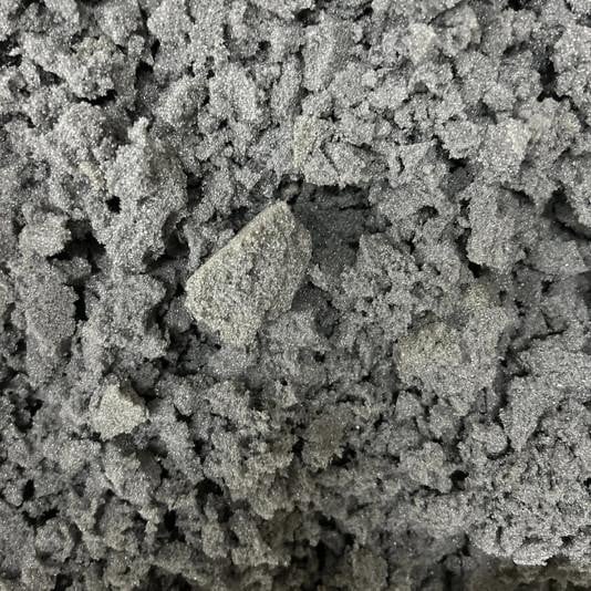 Shredded Memory Foam, close-up image showing small, crumbly pieces of soft, gray foam material used for mattress cushioning or filling.