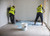 Two installers in hi-viz jackets using Ardex P51 Primer to prime a floor ready for tiling, supplied by Tile Fix Direct
