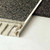 Schluter Schiene E stainless steel tile trim being used to transition between a tile and carpet floor covering.