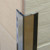A black Genesis EAS Stainless Steel Corner Protector protecting tiled edging