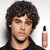 Reuzel Surf Tonic 100ml, a spray bottle of surf tonic for hair styling, positioned beside a man with curly hair.
