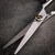 Kobe Apollo Left Handed Hairdressing Scissors, professional sleek stainless steel hair scissors with adjustable dial and ergonomic handle on a dark textured surface.