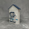 A professionally presented wooden wall-mounted nautical key cabinet box shaped like a seaside beach house with blue gabled roof, lighthouse frame, seagull, fishing net, and boat 3D decorations.