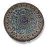 An embossed Persian ceramic plate hanging on a wall, showcasing its intricate relief work and vibrant colors