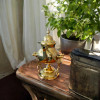A professionally presented traditional brass teapot with an integrated warmer stand and burner set against a clean white background.