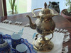 A beautiful handcrafted brass teapot paired with its ornate stand and alcohol-fueled warmer