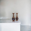 Three-quarter studio perspective capturing the warm, metallic reflection of the hand-spun copper necks and the balanced architectural contours of the 16 cm paired artisan flower vases.
