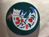 A professional lifestyle presentation shot showing all four round ceramic folk cat coasters arranged neatly in varied jewel-toned backgrounds against a clean backdrop.